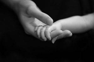 infant holding mother's hand