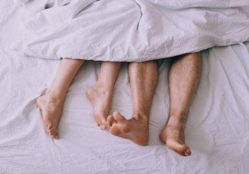 man and woman foot in bed