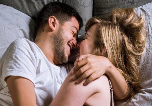 man and woman laughing in bed