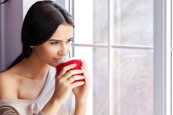 Girl looking out of window having coffee