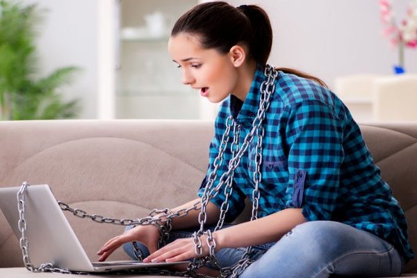 Girl with laptop, both wrapped in chains