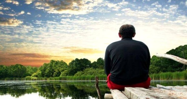 a lonely man sitting by the lake