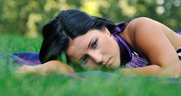 Sad teenager lying in grass