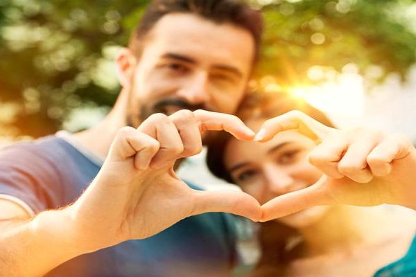 Young man and woman making heart shape with hand