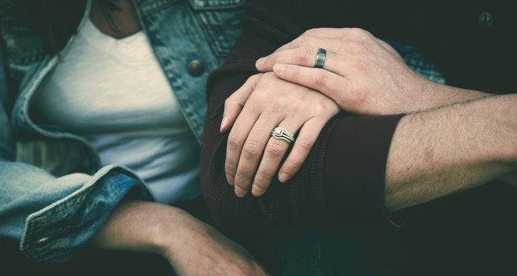 close up of two hands wearing engagement rings
