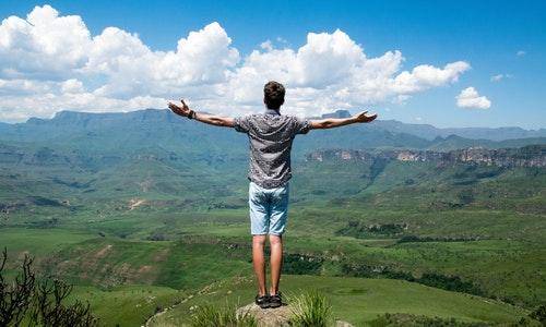man standing at a cliff, arms stretched out