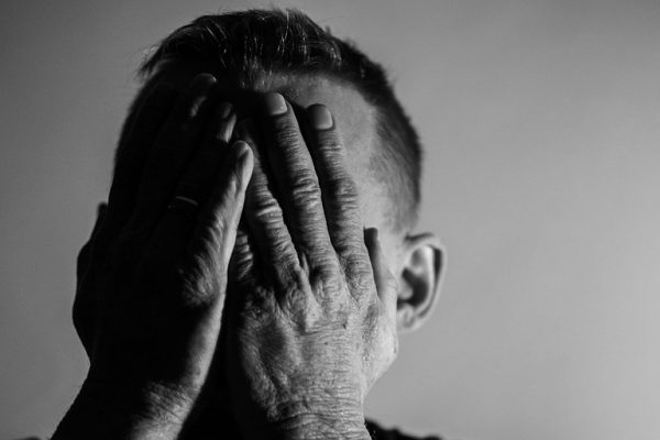 Sad man covering face with hands