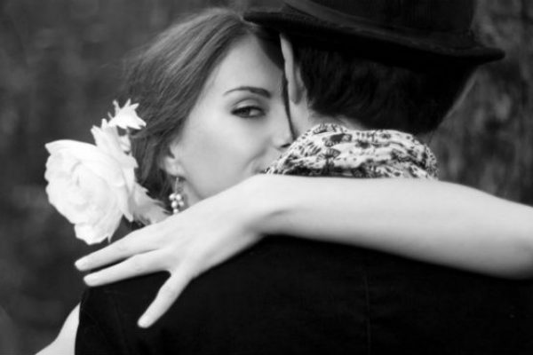 Couple hugs woman looks