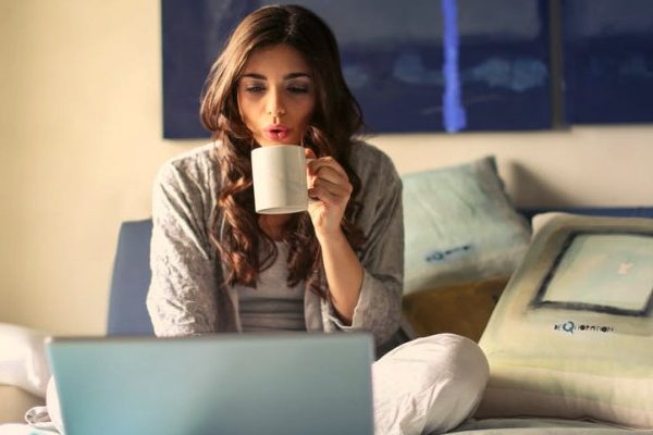 Woman on bed working on laptop