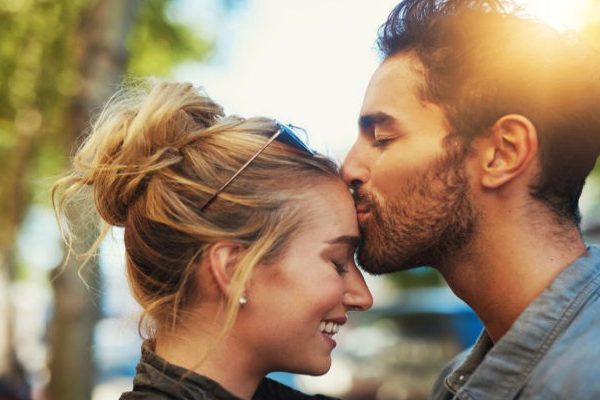 man kissing on forehead of the woman