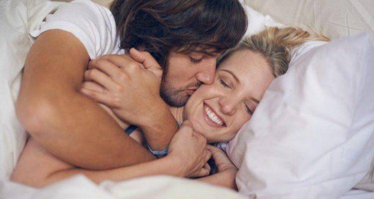 man kissing woman in bed