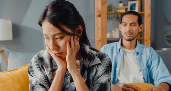 upset-asian-couple-sit-couch-living-room
