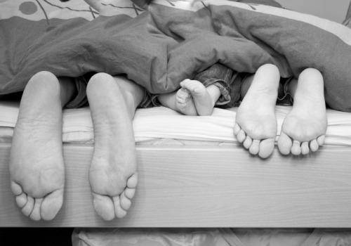 couple sleeping with child in bed