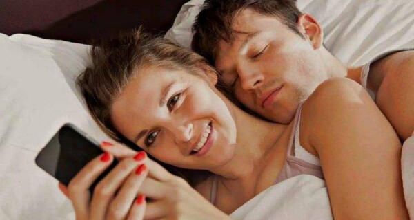 woman checking phone on bed