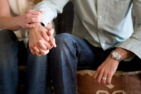 man and woman sitting holding hands