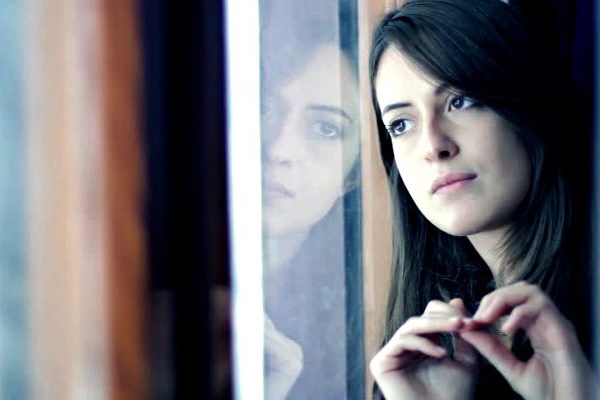 Sad girl near window thinking about something