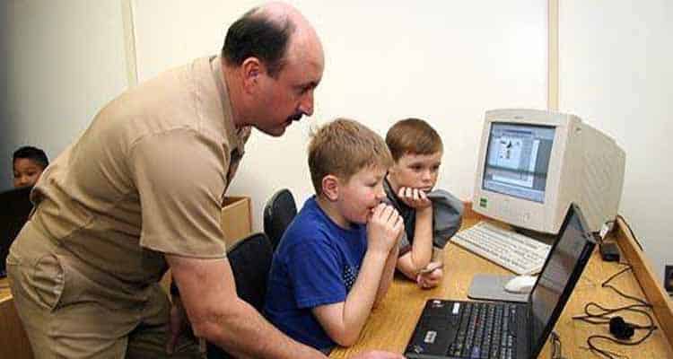 Man helping kids on computer