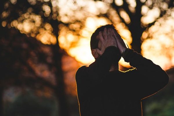 sad man hiding face under hands