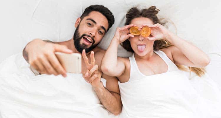 couple taking selfie while in bed
