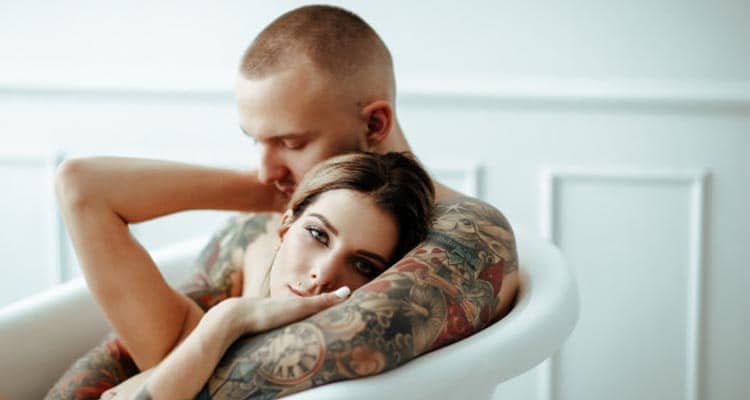 A young couple in love and drawn red hearts taking selfie with a mobile  phone in the handsome guy's hand in front of an empty clear grey wall  background concept | Freestock