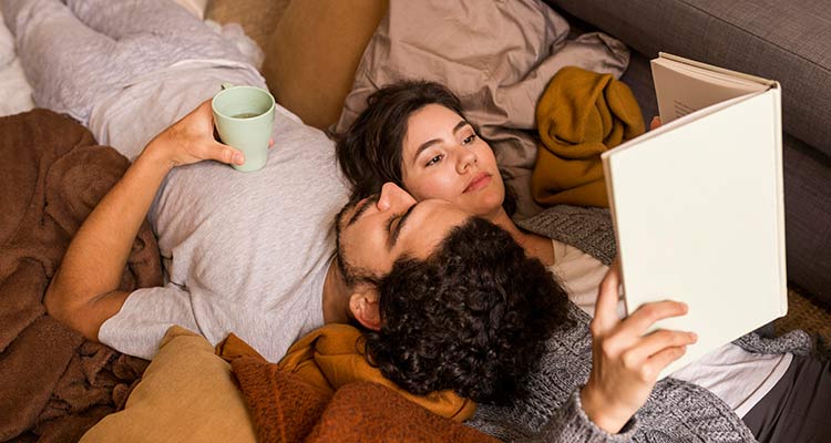couple lying together sofa while reading