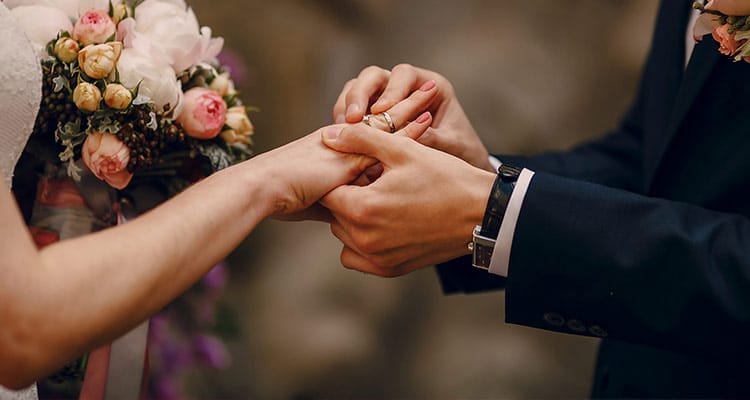 groom putting ring bride's finger