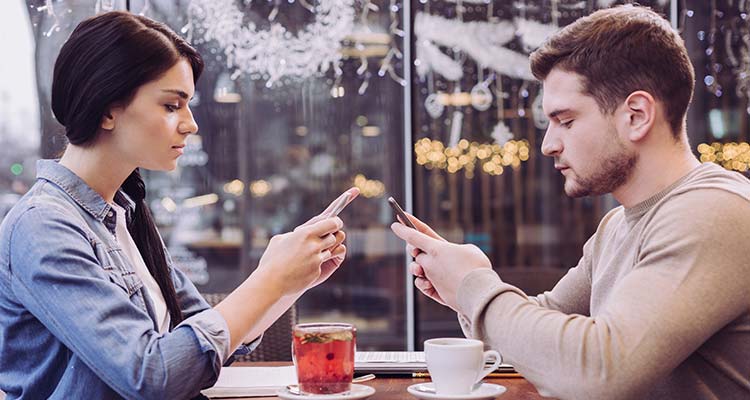 Couple ignoring each other in café