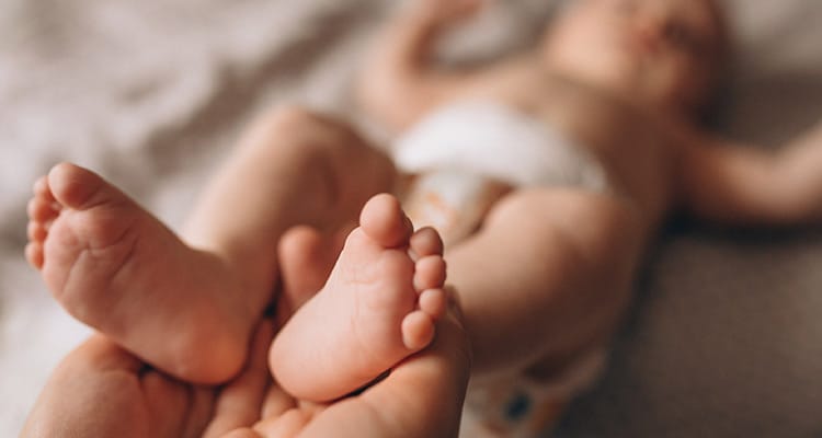 Mother holding newborn baby feet 