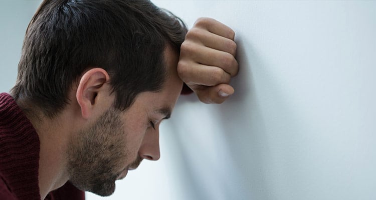 stressed-man-leaning-wall