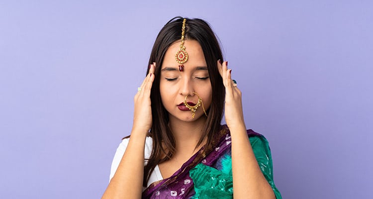 indian woman on purple wall with headache