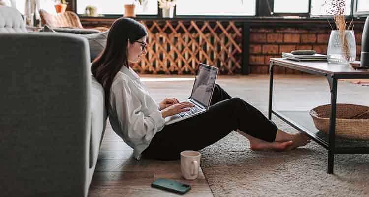 Woman sitting at floor and working on laptop